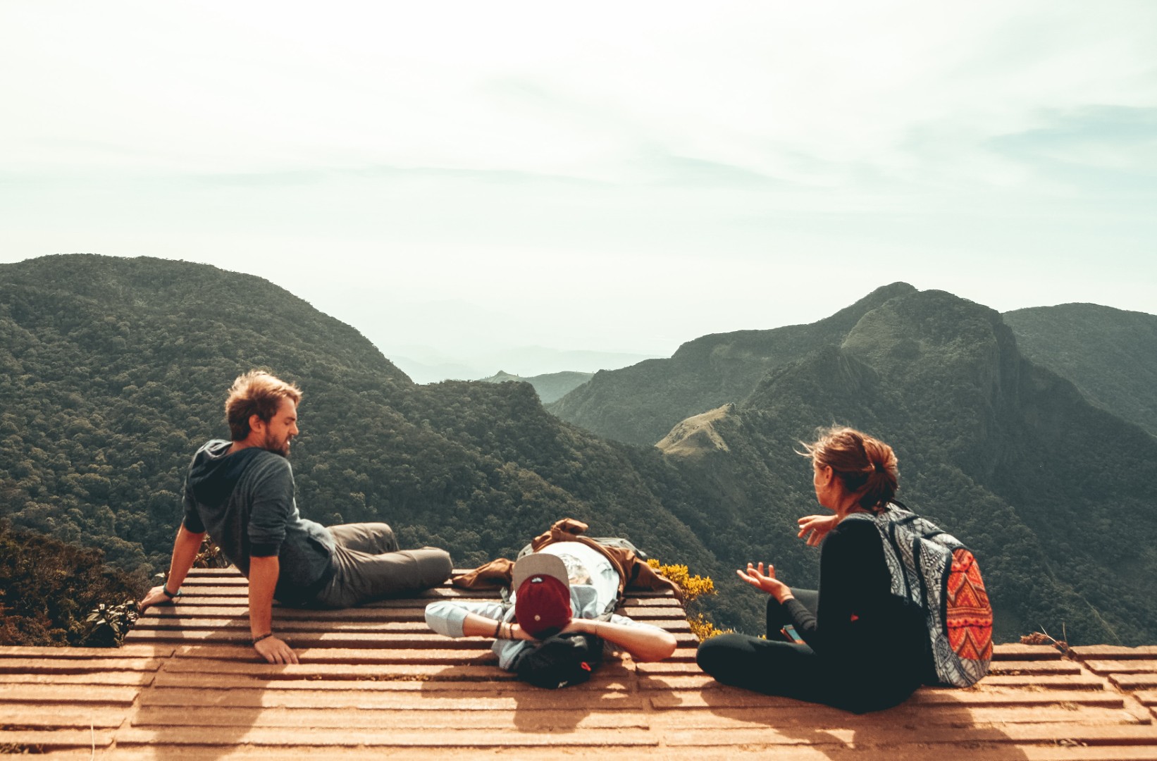 Three friends relaxing at a mountain overlook
